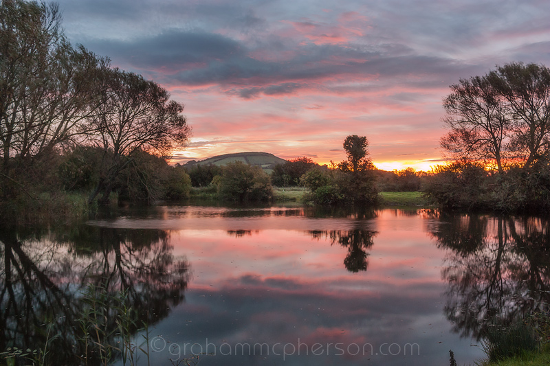 Brent Knoll Dawn Image with red sky reflection in pond